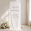 Affection fabric wedding welcome sign hanging full length from a gold stand beside white flowers