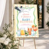 Bottles and Cocktails Baby Shower Welcome Sign on a gold easel beside white flowers