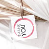 Frocked Up party gift tag with a pink wine-glass ring, styled with a dried palm leaf