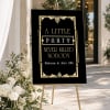 Gatsby Ball Birthday Party Welcome Sign on a gold easel beside white flowers