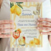 Hands holding a printed Summer Soiree engagement invitation with lemons and an Aperol spritz